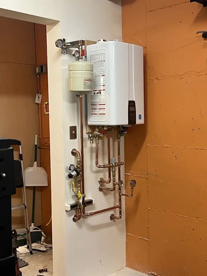 Plumbing technician inspecting water heater connections in Blissfield